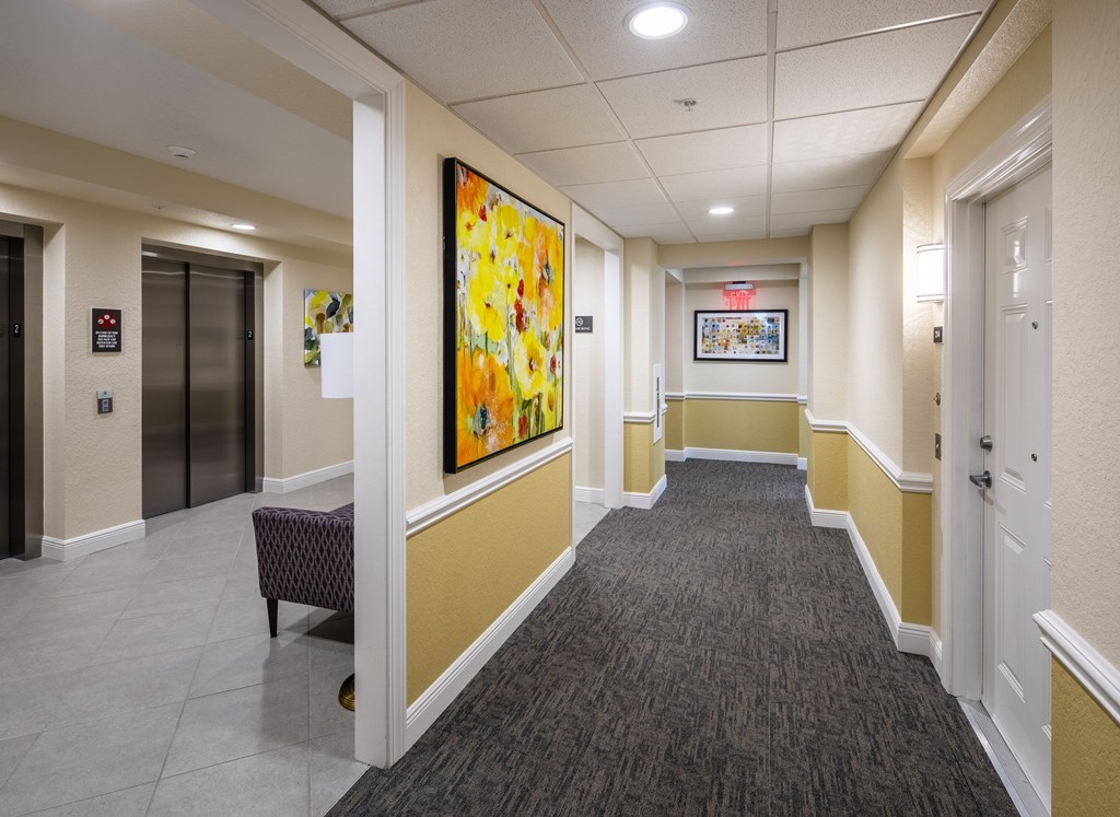 A hallway with a large painting on the wall and a bench on the floor.