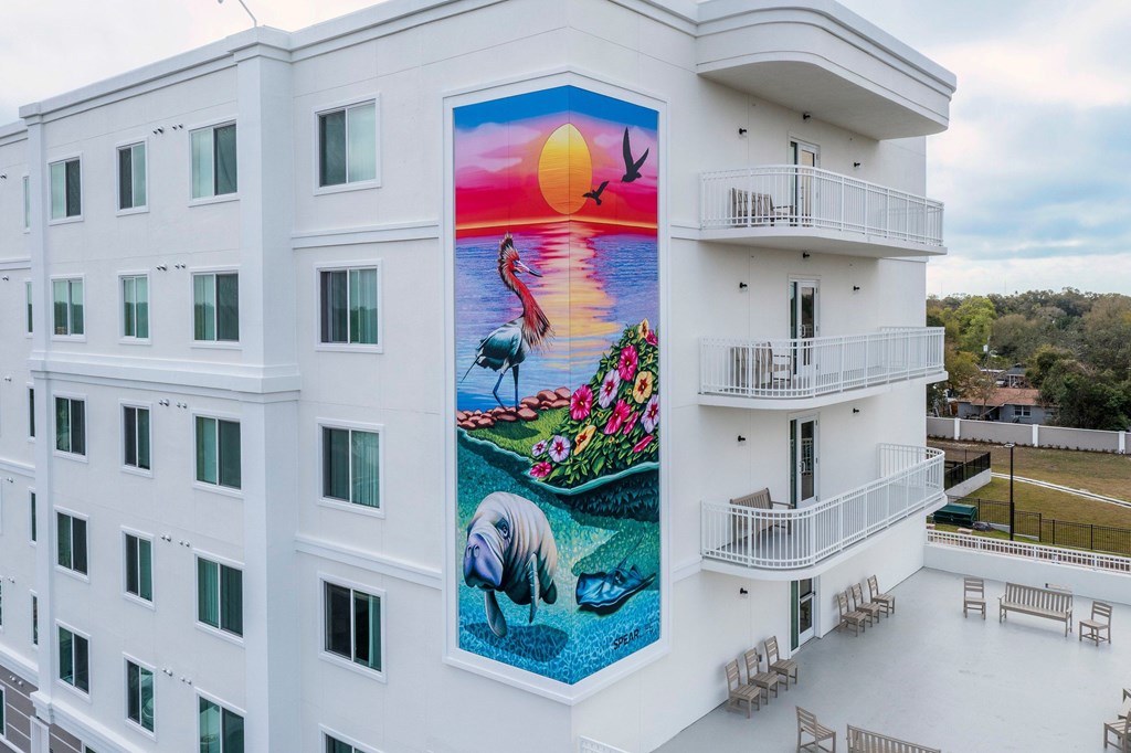 A mural on a building shows a sunset with a bird flying and a fish swimming.
