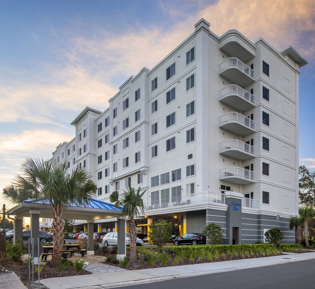 a large white hotel building with palm trees in front of it