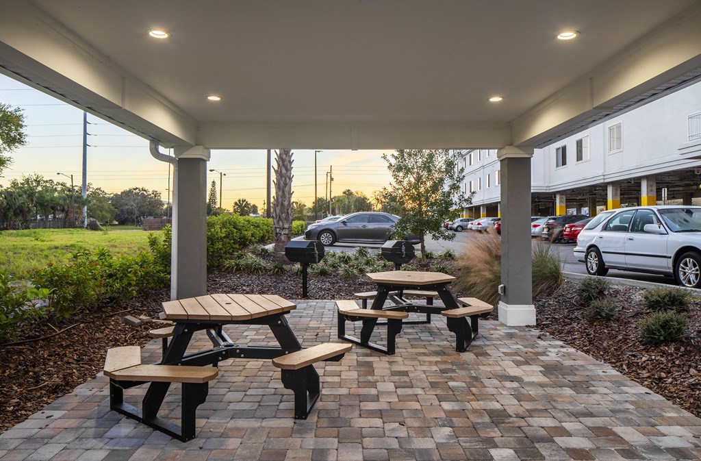 a patio with benches and tables in front of a building