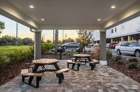 a patio with benches and tables in front of a building