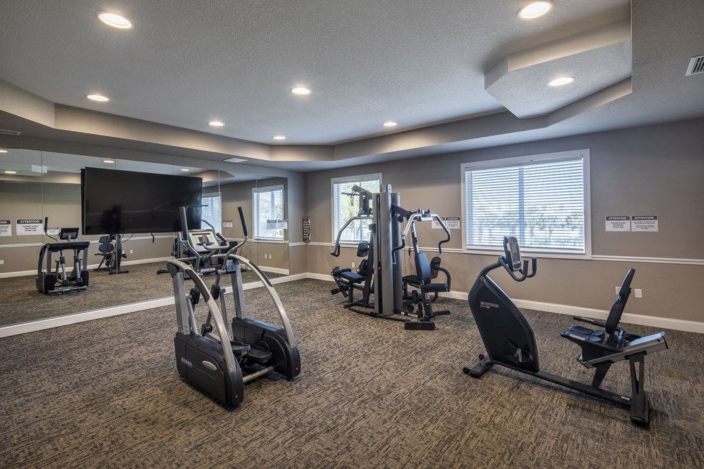 a gym with treadmills and weights and a tv