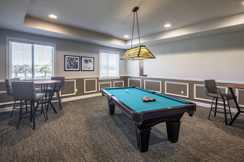 a game room with a pool table and chairs and a lamp