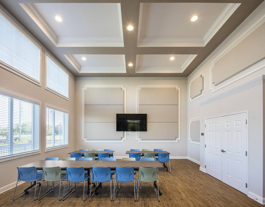 a conference room with tables and chairs and a tv on the wall