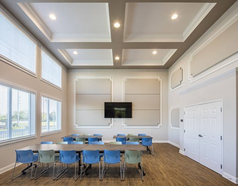 a conference room with tables and chairs and a tv on the wall