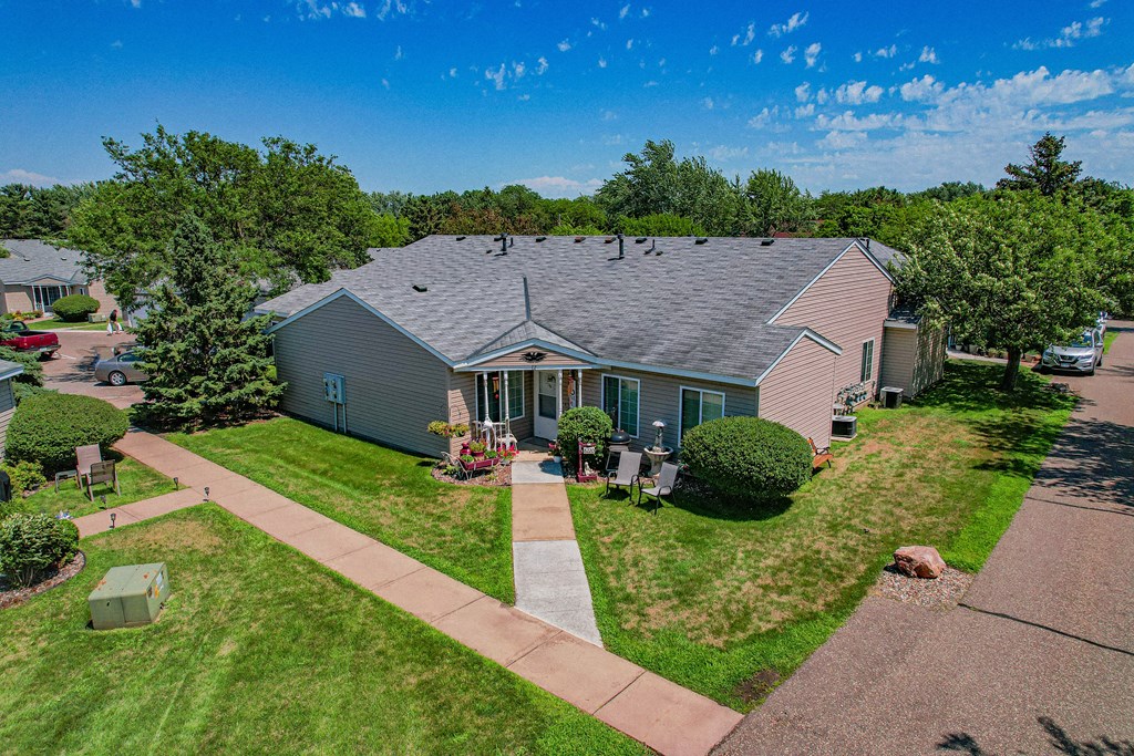 a home with a gray roof and a yard with a sidewalk and trees