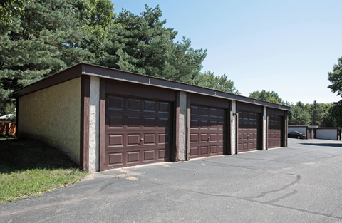 A parking lot with a building and four garage doors.