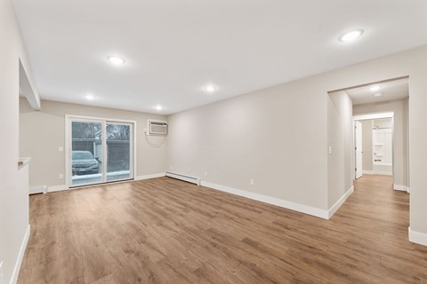 Large living room with wooden floors and white walls.