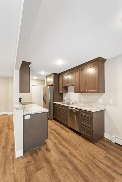 A kitchen with brown cabinets and a white island. Santa Vera Apartments in Chanhassen.