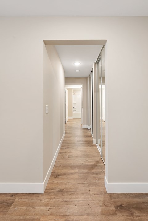 A long hallway with white walls and wood floors.