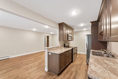 A kitchen with brown cabinets and a granite countertop open concept