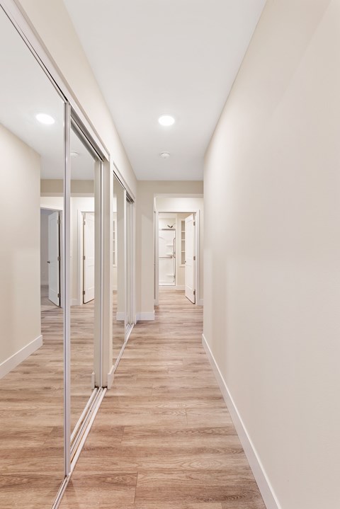 A long hallway with a wood floor and white walls.