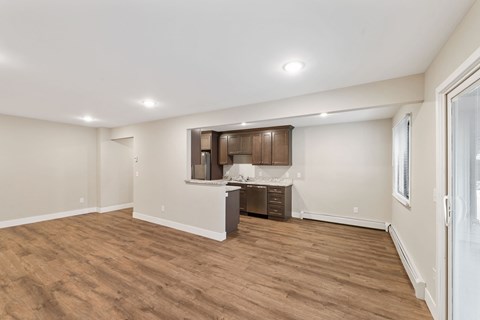 A spacious room with wooden flooring and a kitchenette in the corner.