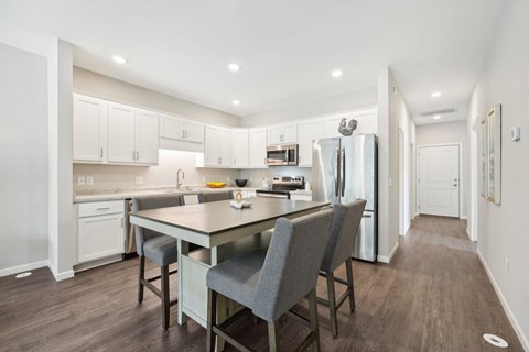 a kitchen with white cabinets and a large island with chairs
