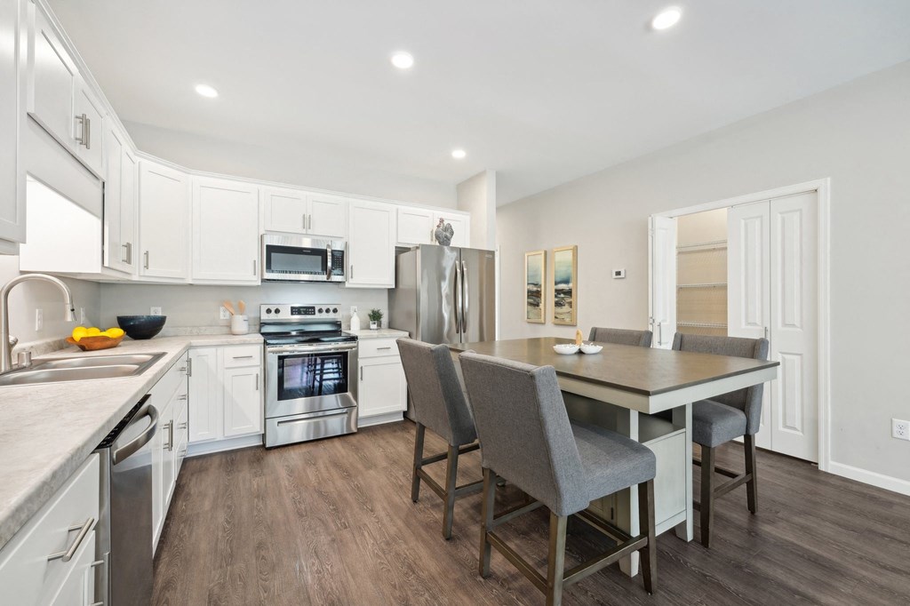 a kitchen and dining room with white cabinets and stainless steel appliances