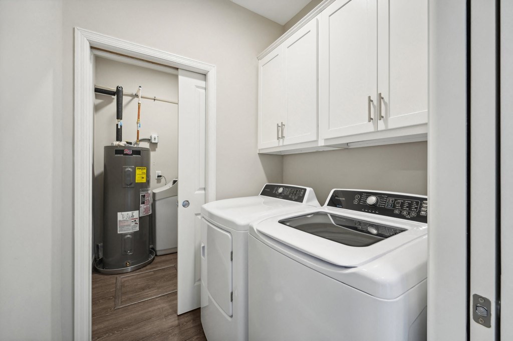 laundry with storage cabinets and a washer and dryer and a boiler