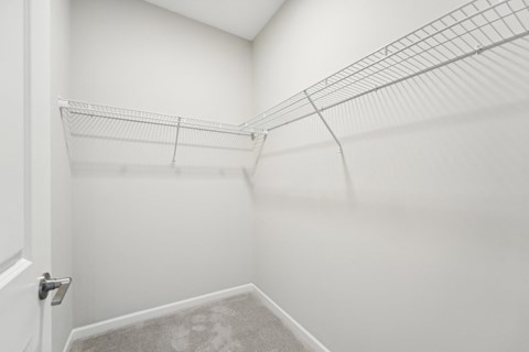 a spacious closet in a home with white walls and a white door