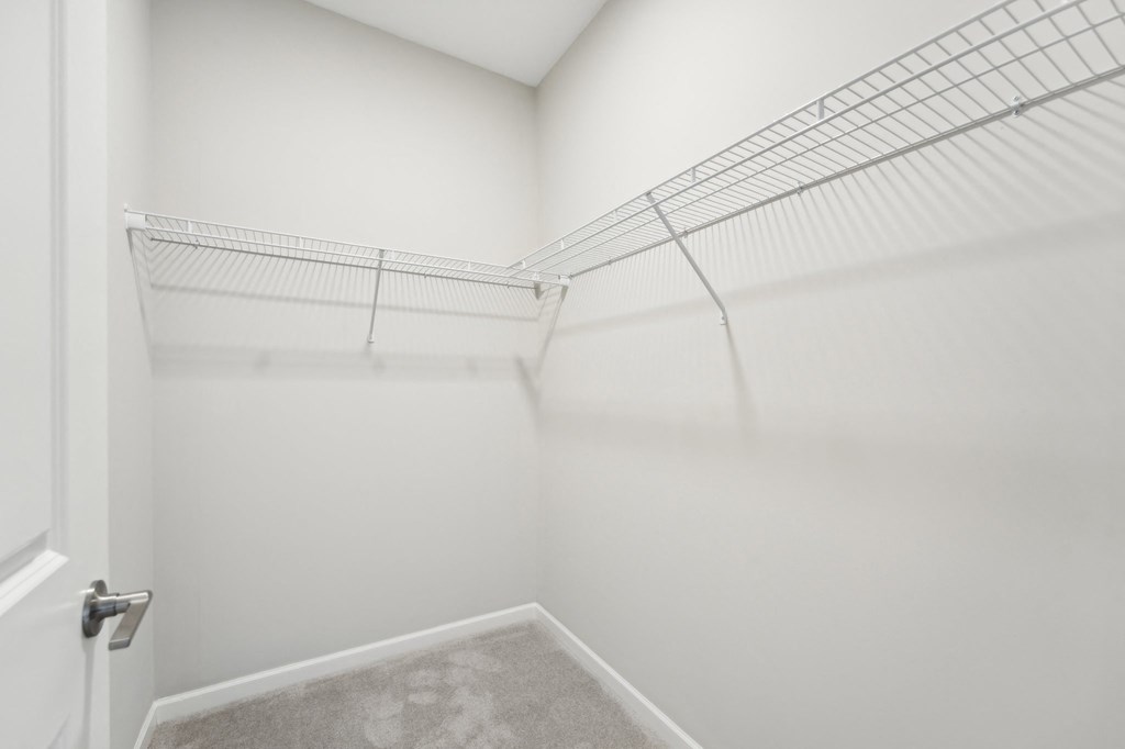 Primary Walk-in closet a spacious closet in a home with white walls and a white door