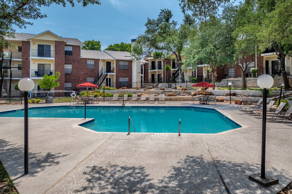 A swimming pool surrounded by apartment buildings and trees.