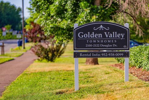 a sign for golden valley townhomes on the side of a sidewalk