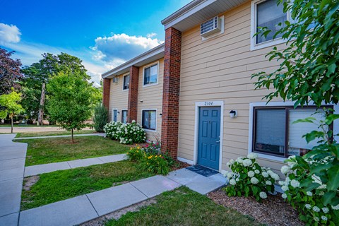 a side view of a house with a blue door and a sidewalk