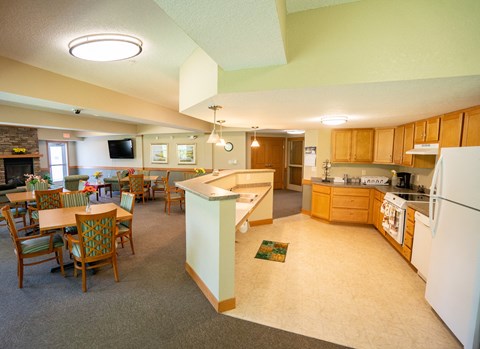 A kitchen with a white refrigerator and wooden chairs.