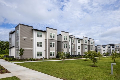 Apartment complex with grey and white buildings and green lawns.