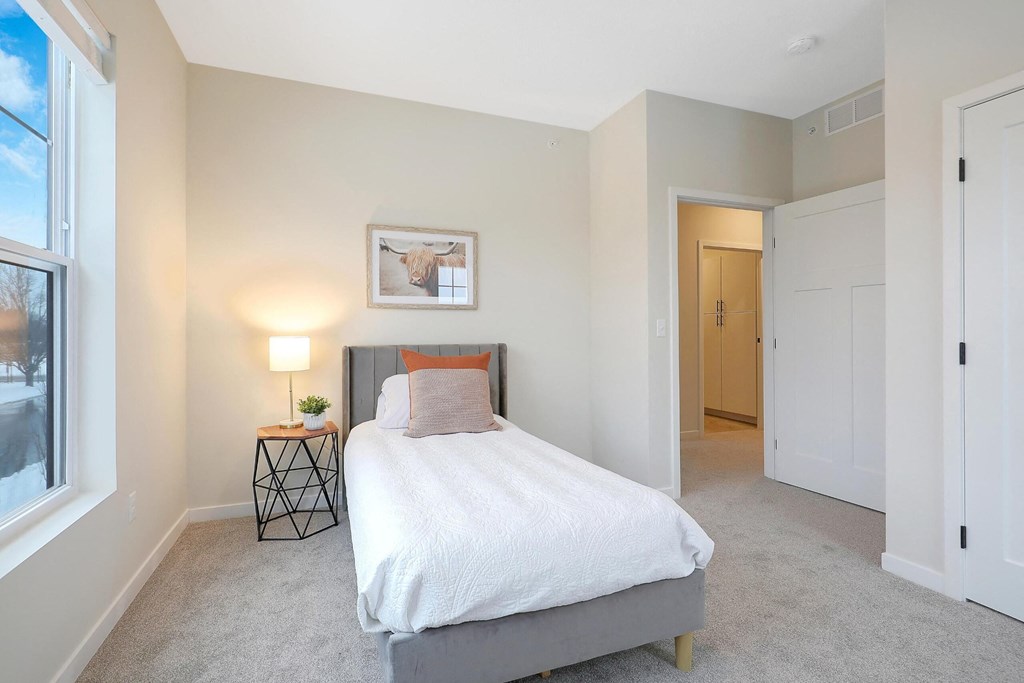 A bedroom with a bed, nightstand, and a painting on the wall.