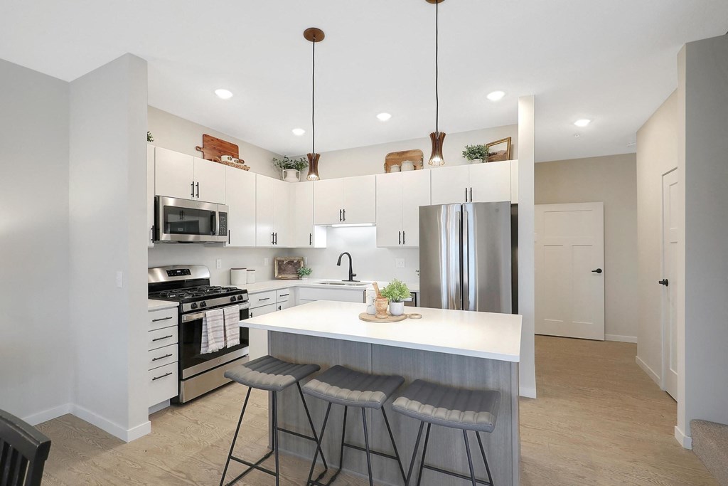 A modern kitchen with a white island and stainless steel appliances.
