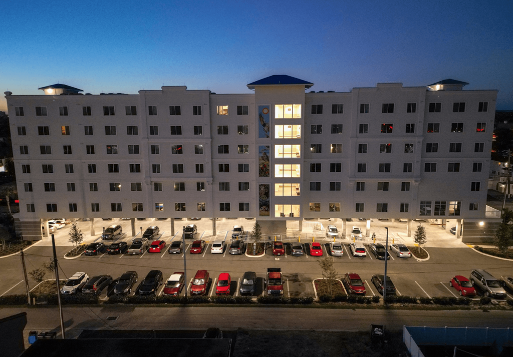 A hotel parking lot is full of cars.