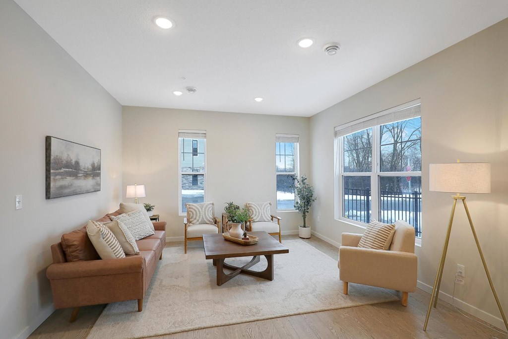 A well-lit living room with a brown couch, a wooden coffee table, and a lamp.
