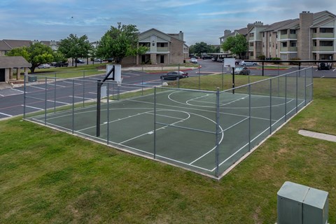 a tennis court in a city neighbourhood with apartments in the background