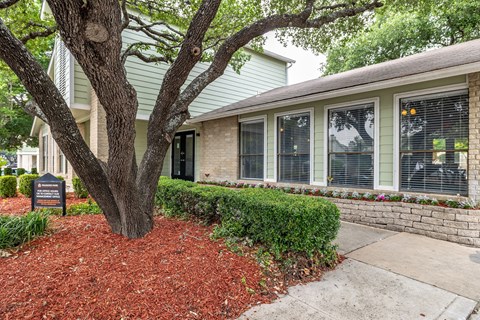 a sidewalk in front of a house with a tree