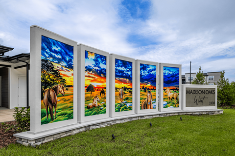A row of four large paintings of horses in a field with the text "MADISON OAKS" on the right.