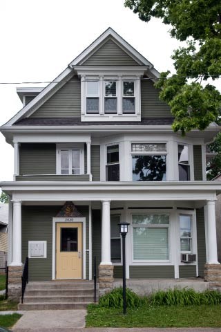 A two story house with a front porch and a yellow door.