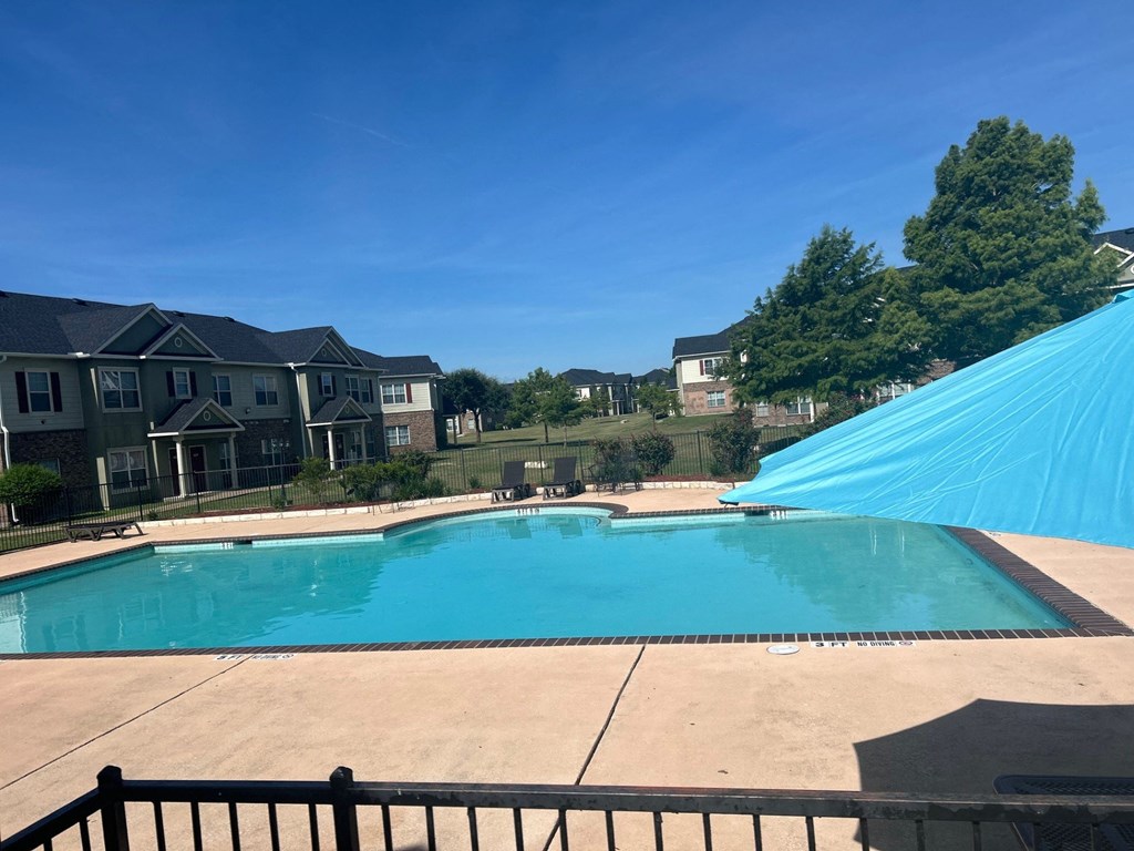 the view of a swimming pool with a blue umbrella and some houses