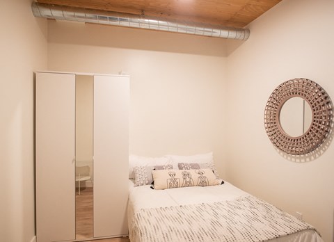 a small bedroom with a bed and a mirror