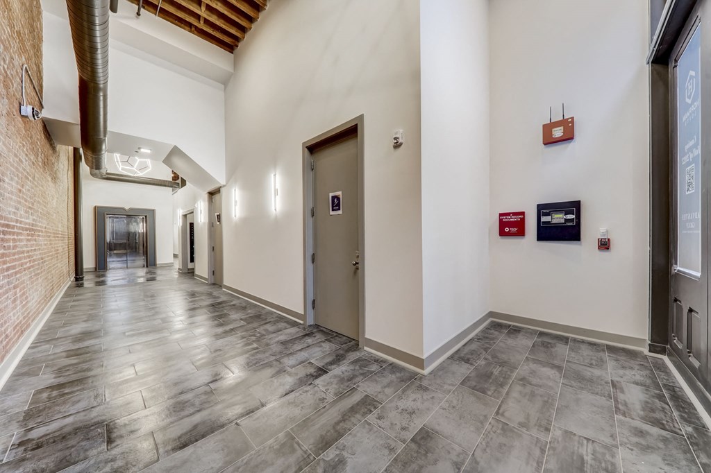 a hallway with white walls and wood floors and elevators