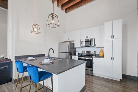 a kitchen with an island with blue chairs and white cabinets