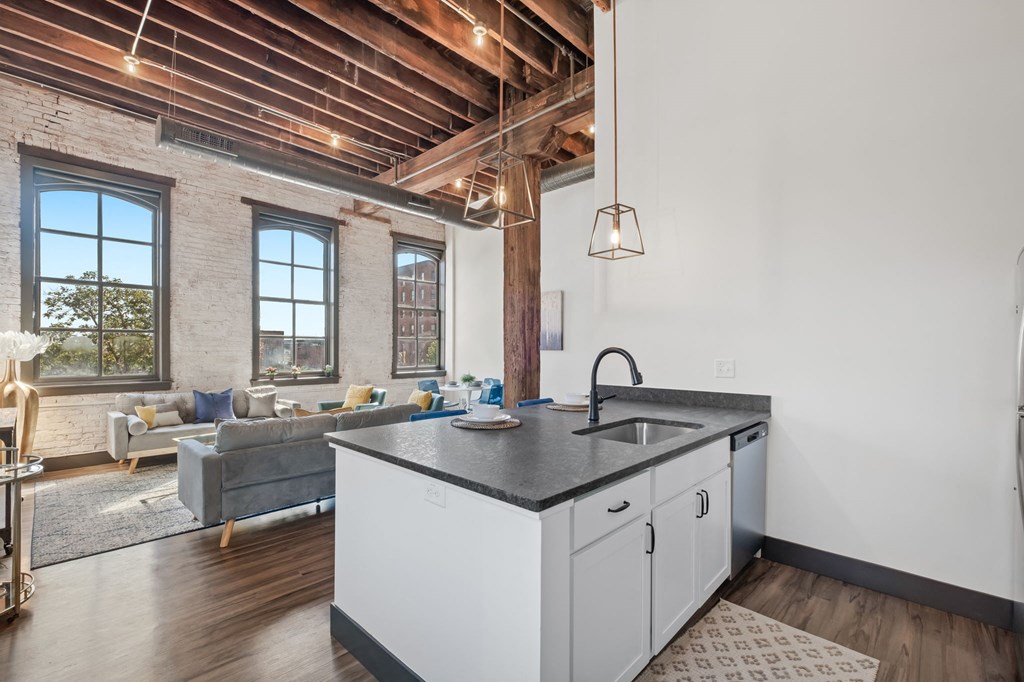 a kitchen with a sink and a counter top in a room with a living room