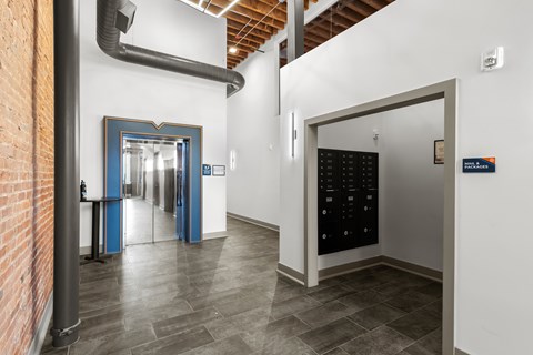 A hallway with a brick wall on the left and a black door on the right.