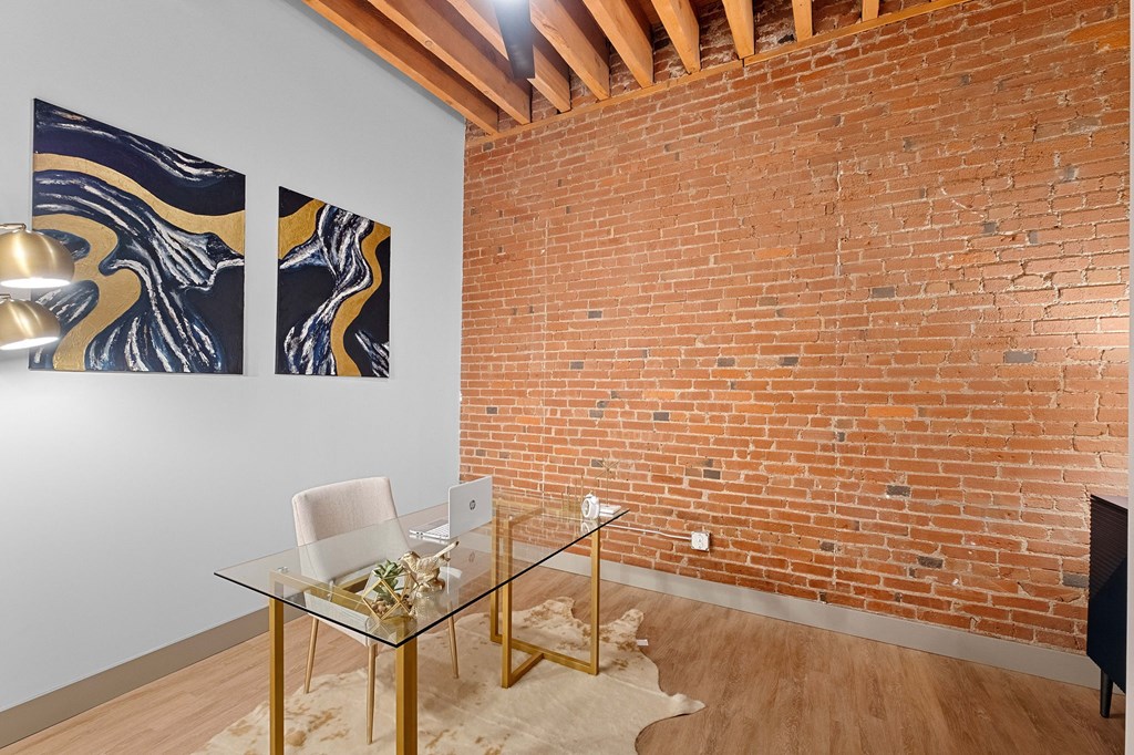 a living room with a glass desk and a brick wall