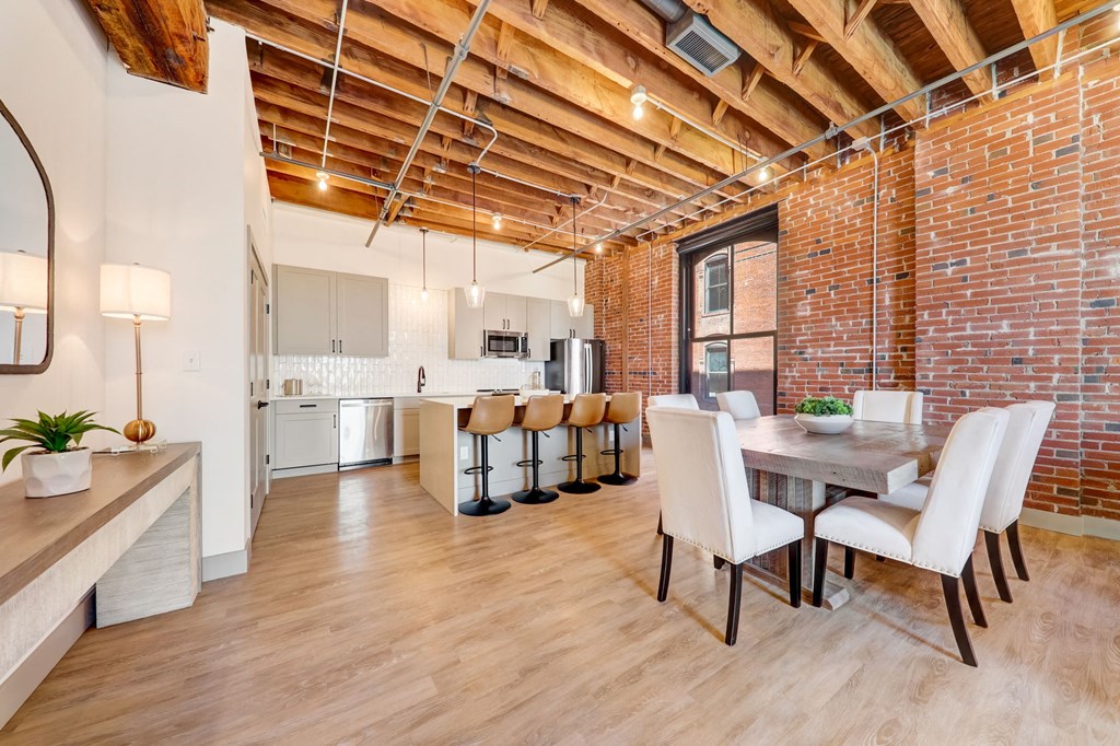 a dining room with a table and chairs and a kitchen in a loft