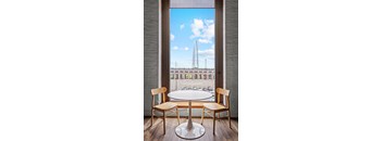 A table with two chairs in front of a window with a view of a bridge.