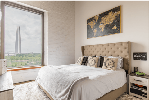 a bedroom with a large window and a bed with pillows