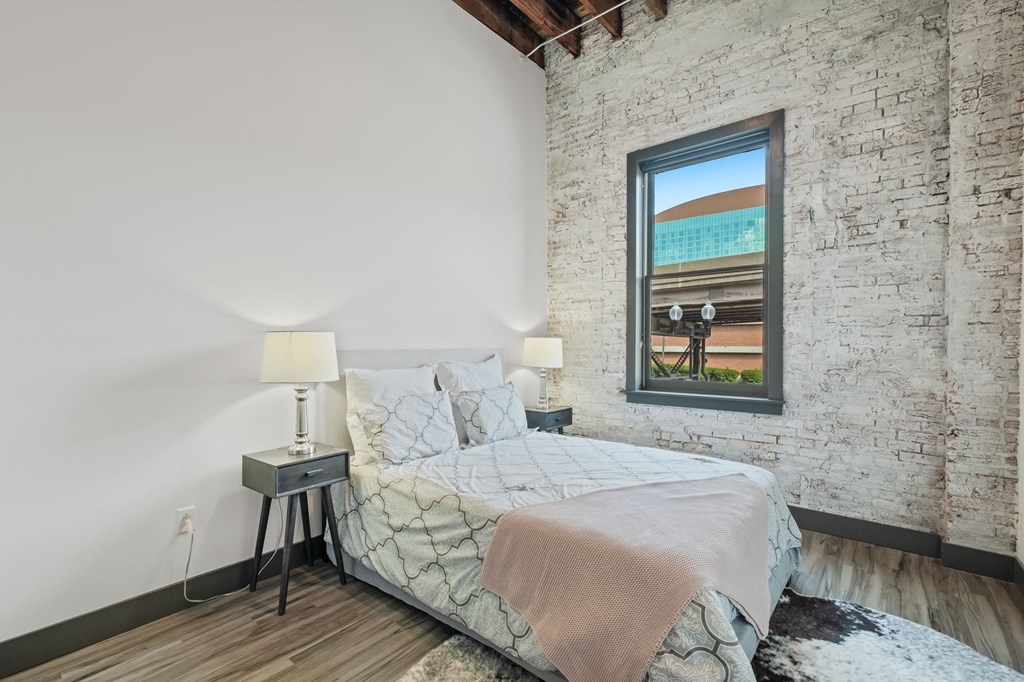 a bedroom with a bed and a exposed brick wall