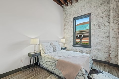 a bedroom with a bed and a exposed brick wall