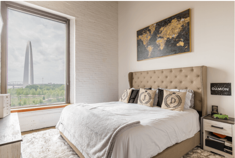 a bedroom with a large window and a bed with pillows