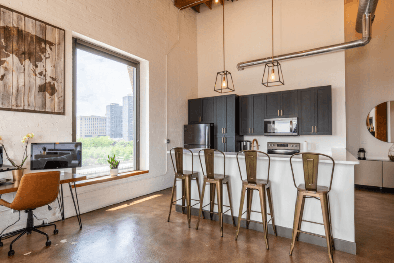a kitchen with bar stools and a counter in a room with a large window