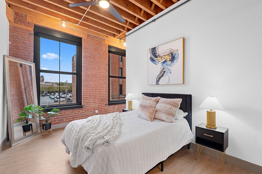 a bedroom with a bed and a brick wall and a large window